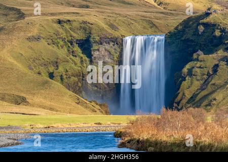 Longue exposition de la célèbre cascade de Skogafoss à distance avec les randonneurs sur le point de vue supérieur Banque D'Images