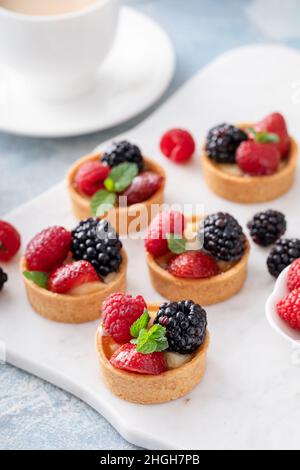 Tartelettes aux baies fraîches avec garniture de crème anglaise et menthe Banque D'Images
