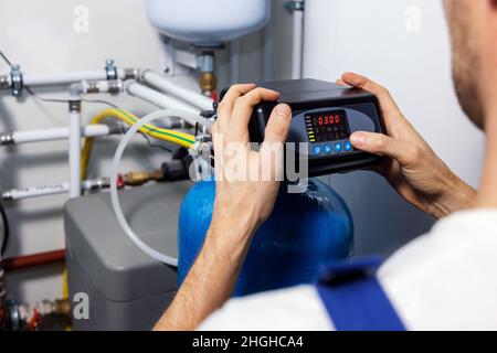 le travailleur a mis en place un système de purification et de filtration de l'eau domestique Banque D'Images