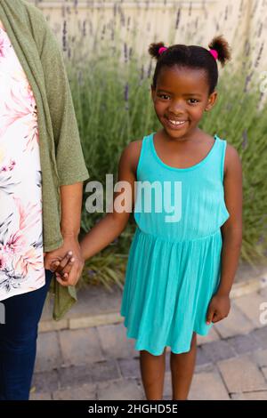 Portrait d'une fille afro-américaine tenant les mains de ses petites-filles tout en se tenant debout à l'extérieur Banque D'Images
