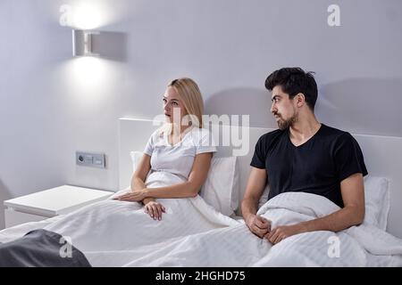 L'homme et la femme caucasienne irrités pendant l'argue à la maison, assis sur le lit ensemble.Les couples européens mariés sont en désaccord dans la chambre à la maison.Querelle Banque D'Images