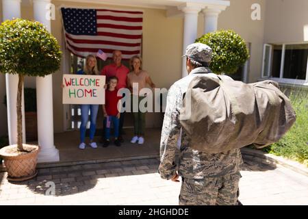 Soldat militaire caucasien avec sac de retour à la maison en marche vers la famille avec étiquette de bienvenue Banque D'Images