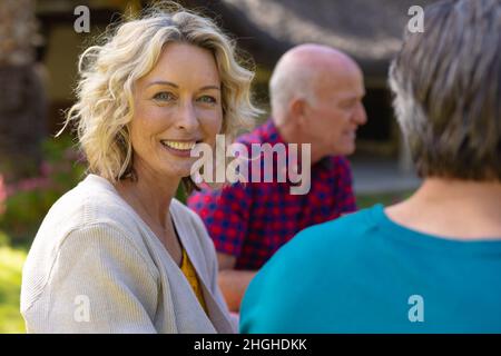 Portrait d'une femme blanche blonde âgée assise avec une famille dans le jardin Banque D'Images