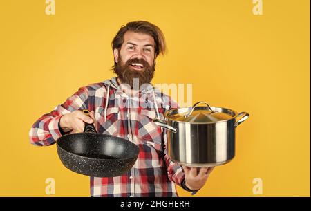 temps de manger. publicité de cuisine.Homme avec une casserole.Un homme tient un récipient de marque neuve.Faire du shopping dans les ustensiles de cuisine. Cuisiner homme mains dans la cuisine. Nourriture Banque D'Images