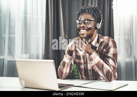 Un jeune professeur d'anglais donne une leçon de vidéo en ligne.Plan du semestre d'étude.Man s'assoit à la table et regarde l'écran de l'ordinateur portable dans casque avec microphone.Gros plan.Photo de haute qualité Banque D'Images