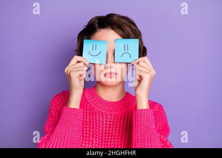 Photo de beau cheveux jeune personne bras tenant des cartes émoji papier couvrant les yeux isolés sur fond violet de couleur Banque D'Images