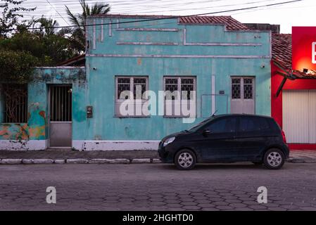 Vieille maison peinte dans la couleur sarcelle claire avec petite voiture noire garée en face au centre du Prado, Bahia, Brésil. Banque D'Images