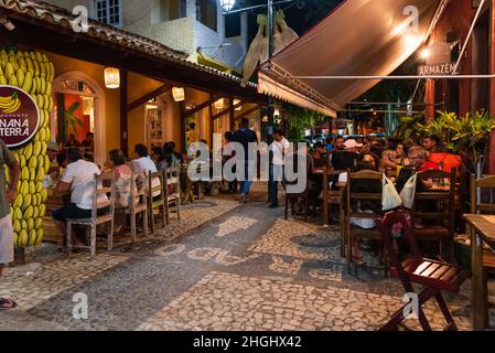 Repas à l'extérieur avec des personnes mangeant, buvant, et marchant au Beco das Garrafas à Prado, Bahia, Brésil. Banque D'Images