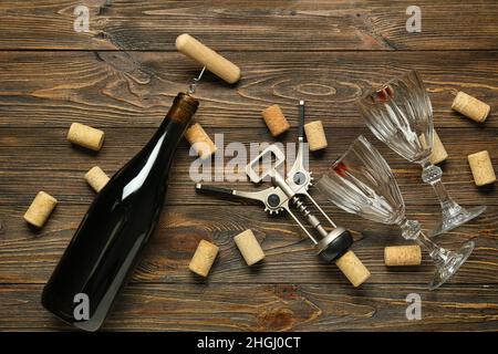 Bouteille de vin, ouvre-bouteilles, bouchons et verres sur fond de bois Banque D'Images