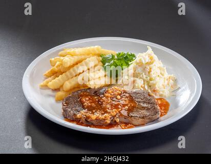 Sirloin fraîchement grillée Steak sauce avec frites et salade servi dans un plat blanc sur fond sombre Banque D'Images