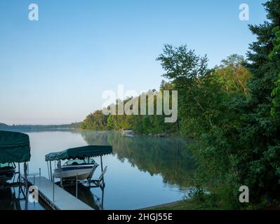 Belle scène de lac du Minnesota sur une matinée calme et claire avec des eaux calmes et un couple de bateaux de plaisance sur la rive. Banque D'Images