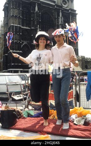 Un jeune couple s'étirant les jambes après avoir dormi sur le trottoir à l'extérieur de l'abbaye de Westminster pour le mariage du Prince Andrew et de Sarah Ferguson le 23rd 1986 juillet Banque D'Images