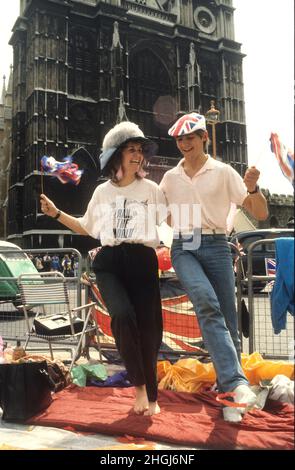 Un jeune couple s'étirant les jambes après avoir dormi sur le trottoir à l'extérieur de l'abbaye de Westminster pour le mariage du Prince Andrew et de Sarah Ferguson le 23rd 1986 juillet Banque D'Images