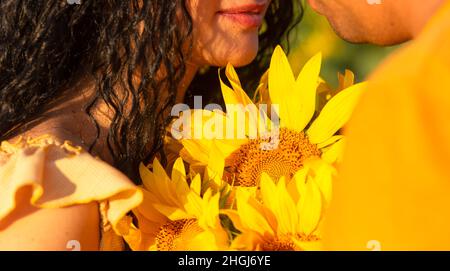 couple tenant un bouquet de tournesols debout ensemble dans un champ au soleil couchant, vacances d'été Banque D'Images