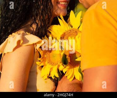 couple tenant un bouquet de tournesols debout ensemble dans un champ au soleil couchant, vacances d'été Banque D'Images