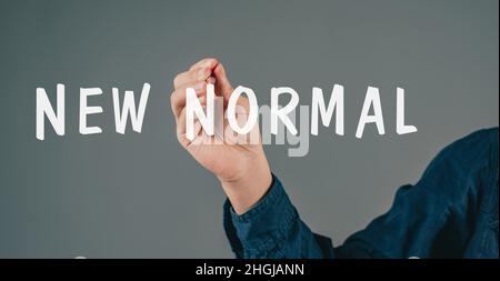 Le jeune homme écrit les mots nouveau normal, post covid-19 pandémie, changement de mode de vie, vie différente, début de transformation Banque D'Images