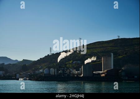 Deux cheminées émettant de la fumée blanche à l'aube sur la mer Banque D'Images