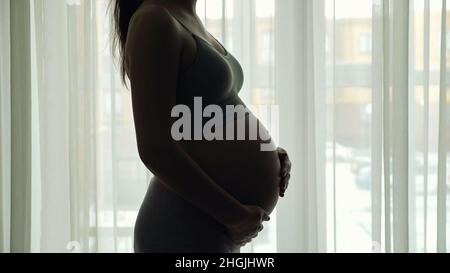 La silhouette de femme enceinte dans les vêtements de sport se déplace grand ventre Banque D'Images