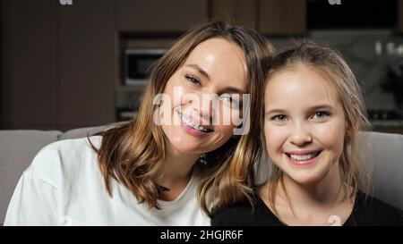 La mère et la fille sourient largement en regardant dans l'appareil photo à la maison Banque D'Images