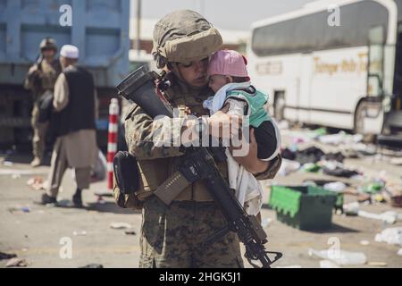 210828-M-AU949-0271 AÉROPORT INTERNATIONAL HAMID KARZAÏ (Afghanistan) (28 août 2021) Une marine américaine avec la 24e unité expéditionnaire maritime (UMM) transporte un bébé comme processus de la famille par le biais du Centre de contrôle d'évacuation (ECC) lors d'une évacuation à l'aéroport international Hamid Karzaï, Kaboul, Afghanistan, août 28. Les membres du service américain aident le ministère d'État à effectuer une opération d'évacuation (NEO) non combattue en Afghanistan. Banque D'Images