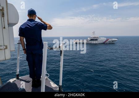 Un membre de l'équipage du Cutter Munro de la Garde côtière des États-Unis salue un navire de la Garde côtière des Philippines qui transite le long du Munro dans la mer des Philippines de l'Ouest, le 31 août 2021. Les membres de la Garde côtière à bord du Munro et de la Garde côtière des Philippines ont participé à des opérations et exercices bilatéraux qui comprenaient des communications et des opérations de recherche et de sauvetage. Banque D'Images