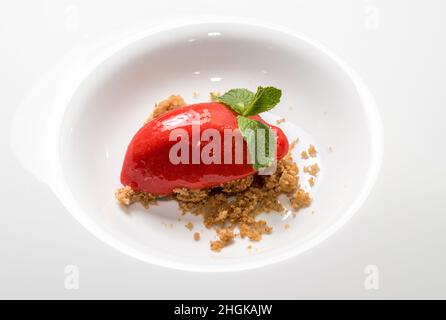 Quenelle de glace à sorbet aux baies maison en forme de feuilles de menthe sur un biscuit émietté Banque D'Images