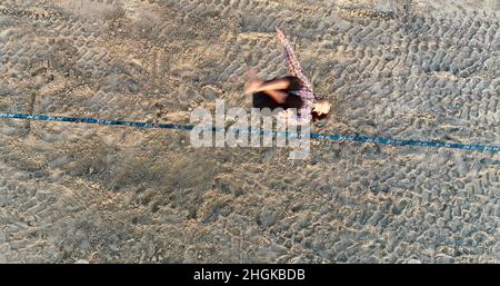 Vue aérienne au-dessus de l'homme en train de desserrer l'équilibrage sur la corde et de faire des acrobaties, démontrant l'agilité, Pacific Beach à San Diego, Californie, États-Unis Banque D'Images