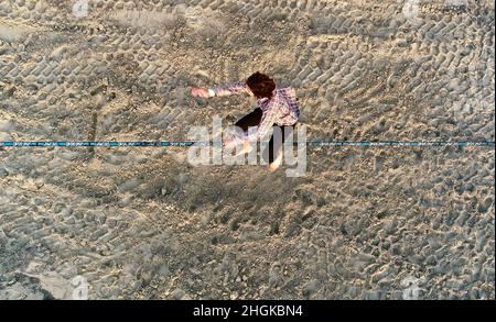Vue aérienne au-dessus de l'homme en train de desserrer l'équilibrage sur la corde et de faire des acrobaties, démontrant l'agilité, Pacific Beach à San Diego, Californie, États-Unis Banque D'Images