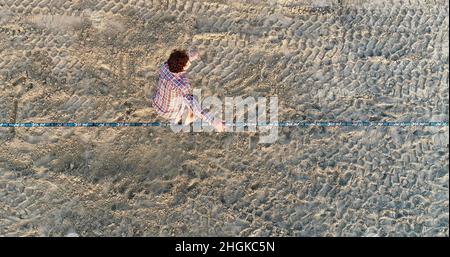 Vue aérienne au-dessus de l'homme en train de desserrer l'équilibrage sur la corde et de faire des acrobaties, démontrant l'agilité, Pacific Beach à San Diego, Californie, États-Unis Banque D'Images