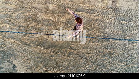 Vue aérienne au-dessus de l'homme en train de desserrer l'équilibrage sur la corde et de faire des acrobaties, démontrant l'agilité, Pacific Beach à San Diego, Californie, États-Unis Banque D'Images