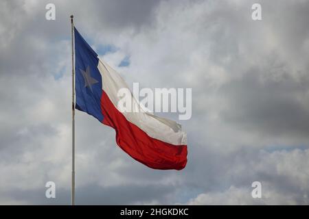 Drapeau de l'État du Texas sur le poteau agitant dans l'aile contre des nuages blancs Banque D'Images