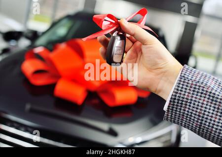 Un homme donne une clé de voiture avec un gros nœud rouge à une