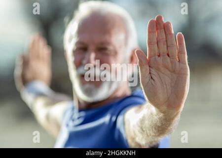 Gros plan de l'homme âgé main étirant les bras, faisant du yoga ou du tai chi à l'extérieur Banque D'Images