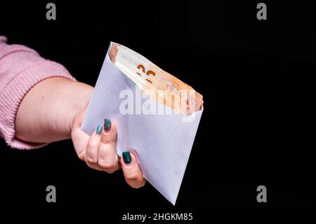 main tenant des billets en euros dans l'enveloppe isolée sur fond noir, corruption, pot-de-vin, gros plan Banque D'Images