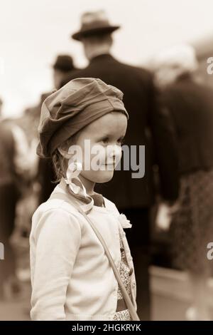 Petite fille habillée comme évacuée en temps de guerre en 1940, costume des années 1940 debout sur le quai de la gare d'époque à l'événement ww2 reconstitution, Royaume-Uni. Banque D'Images