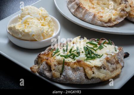 Helsinki / Finlande - 21 JANVIER 2022 : aliments traditionnels finlandais - tartes Karéliennes fraîches avec beurre d'œuf et ciboulette sur fond noir. Banque D'Images