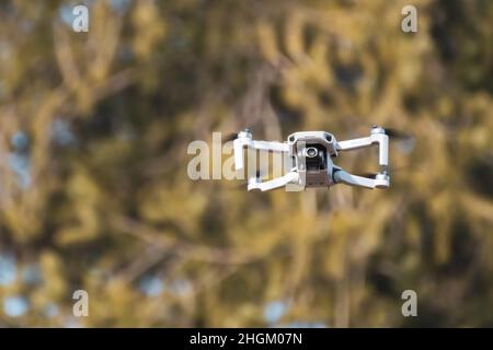 Kharkiv, Ukraine - 6 mars 2021 : DDJI Mavic Mini 2 drone, volant dans une forêt ensoleillée.Nouveau périphérique quadcopter survolant avec un arrière-plan flou vert chaud Banque D'Images
