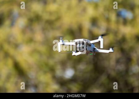 Kharkiv, Ukraine - 6 mars 2021: DDJI Mavic Mini 2 drone, volant dans la verdure ensoleillée.Nouveau périphérique quadcopter survolant avec un arrière-plan vert flou Banque D'Images