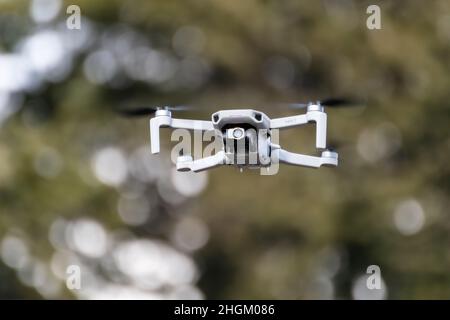 Kharkiv, Ukraine - 6 mars 2021 : DDJI Mavic Mini 2 drone, volant en forêt.Nouveau dispositif quadcopter planant avec des arbres flous, arrière-plan bokeh Banque D'Images