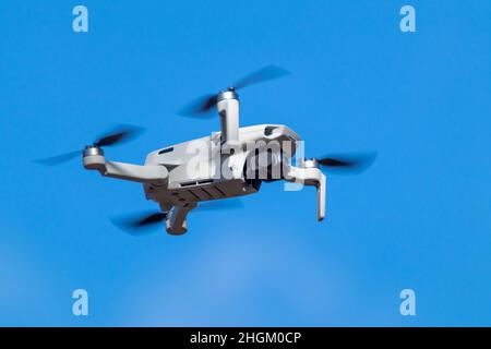 Kharkiv, Ukraine - 6 mars 2021: DDJI Mavic Mini 2 drone, volant dans la lumière du jour ensoleillée.Nouveau périphérique quadcopter survolant sur fond bleu ciel flou Banque D'Images