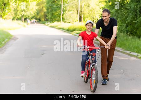 Le père aimant faire du vélo pour fille d'enseignement Banque D'Images