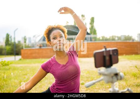 bonne femme mexicaine blogueur de sport avec appareil photo sur trépied enregistrement de l'entraînement de fitness en plein air Banque D'Images