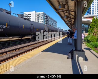 Les navetteurs attendant le train du matin et le train de marchandises garés avec wagons-citernes.Gare de Oak Park Metra, Illinois. Banque D'Images