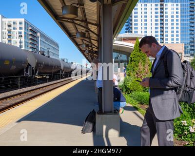 Les navetteurs attendant le train du matin et le train de marchandises garés avec wagons-citernes.Gare de Oak Park Metra, Illinois. Banque D'Images