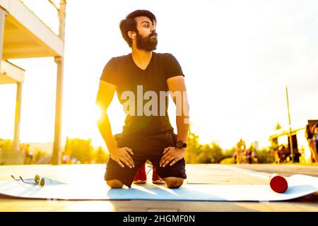 homme hispanique en coton noir t-shirt prêt à yoga au coucher du soleil dans le parc d'été lumière dorée extérieure Banque D'Images