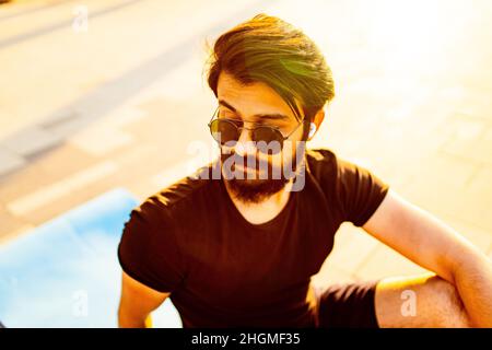 beau homme dans des lunettes de soleil dans le parc d'été aux lumières dorées du coucher du soleil Banque D'Images
