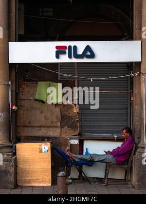 MUMBAI, INDE - 26 novembre 2021 : un vendeur de rue non identifié se détend pendant les heures de repos dans les rues du centre-ville dans le sud de mumbai. Banque D'Images