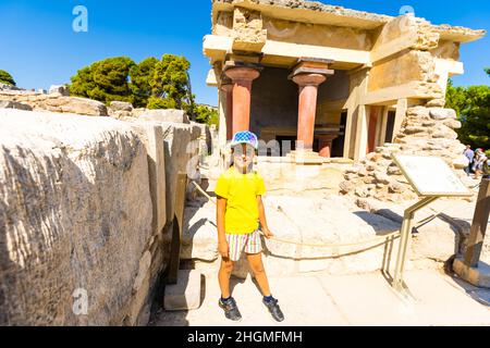 Une petite fille s'arrête pour prendre une photo d'œuvres d'art sur les murs du palais minoen à Knossos. Crète, Grèce Banque D'Images