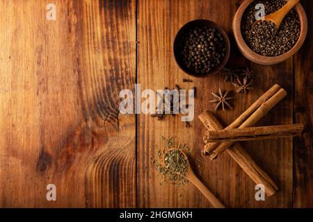 Diverses épices sur fond de bois rustique.Poivre, cardamome, clou de girofle, cannelle, anis étoilé,persil déshydraté.Pose à plat Banque D'Images