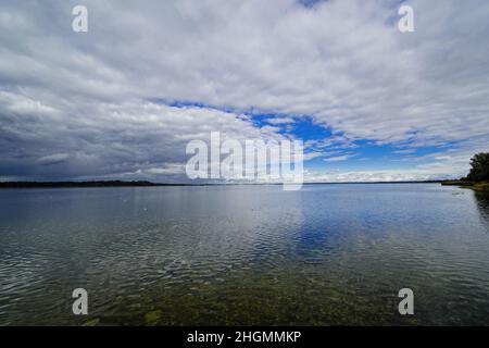 Des nuages de tempête sombres s'accumulent sur un grand lac. Banque D'Images